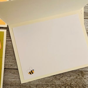 Puede incluir: Tarjeta de felicitaci&oacute;n en blanco con una ilustraci&oacute;n de abeja amarilla y negra en el interior.