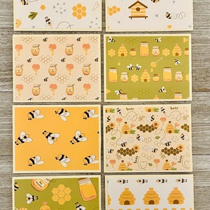 Puede incluir: Conjunto de seis tarjetas de felicitaci&oacute;n con tem&aacute;tica de abejas con diferentes patrones. Las tarjetas presentan abeilles, panales, tarros de miel, colmenas y flores. Las tarjetas est&aacute;n todas en una gama de colores amarillos y verdes.