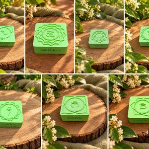May include: A set of seven square, light green blocks, each featuring a unique embossed chakra symbol and corresponding text on the side. The symbols include the Om sign, geometric patterns, and various Sanskrit-inspired icons on a flat surface.