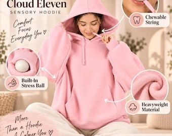 Puede incluir: Una sudadera con capucha rosa claro que cuenta con una pelota antiestrés integrada en el puño, un cordón masticable unido a la capucha y tela pesada. El texto en la imagen incluye Cloud Eleven Sensory Hoodie, Chewable String, Built-In Stress Ball y Heavyweight Material.