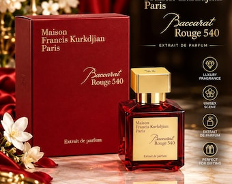 May include: A red glass perfume bottle with a gold cap and a square label reading Maison Francis Kurkdjian Paris Baccarat Rouge 540 Extrait de parfum, accompanied by a matching red rectangular box with identical gold text branding.