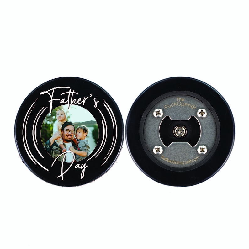 Peut inclure: Ouvre-bouteille en forme de rondelle de hockey noir avec un insert photo et le texte "Father's Day" en &eacute;criture blanche. Le dos de la rondelle porte le texte "The Puck Opener" et "BuffaloBottleCraft.com" en or.