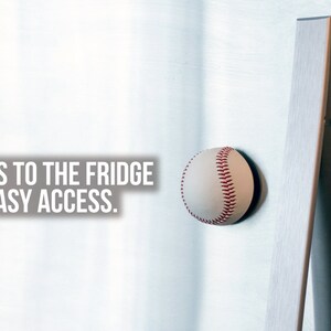 May include: A white baseball with red stitching is attached to a silver refrigerator with a magnet. The text "STICKS TO THE FRIDGE FOR EASY ACCESS." is visible in the image.
