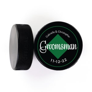 May include: Black and green hockey puck with the text "Gabrielle & Christopher Groomsman 7-12-22" printed on it.