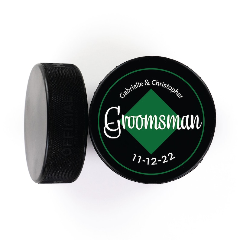 May include: Black and green hockey puck with the text "Gabrielle & Christopher Groomsman 7-12-22" printed on it.