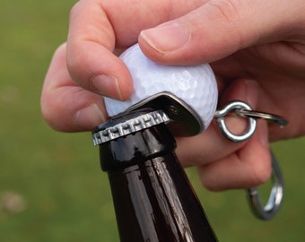 May include: A golf ball bottle opener with a silver metal ring and a black bottle.