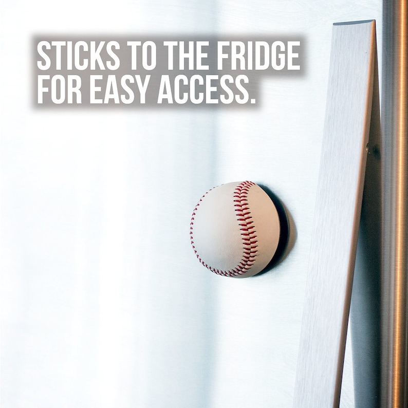 Pu&ograve; includere: Una palla da baseball bianca con cuciture rosse &egrave; attaccata a un frigorifero argentato con una calamita. Il testo "STICKS TO THE FRIDGE FOR EASY ACCESS." &egrave; stampato sopra la palla.