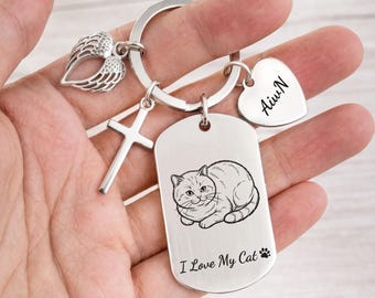 May include: A silver-toned metal keychain featuring a rectangular dog tag engraved with a cat illustration and the text "I Love My Cat" with a paw print. It includes a heart-shaped charm engraved with "AiwN", a cross charm, and a wing charm.