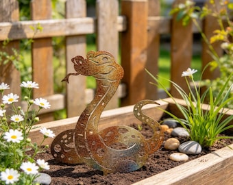 May include: A decorative metal snake garden stake featuring a weathered, multi-toned brown and copper finish with a crackled texture. The snake is depicted in an upright, coiled position with its head raised and tongue extended, designed for placement in soil.