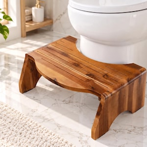 May include: A curved wooden bathroom stool with a natural brown wood grain finish and horizontal slats on the top surface. The stool features a U-shaped cutout designed to fit around the base of a white toilet, supported by two side legs.