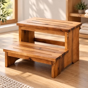 May include: A two-step wooden stool featuring a natural brown finish with visible wood grain. The stool has two horizontal platforms, each with two parallel rectangular cutouts, supported by solid side panels and a central crossbar.