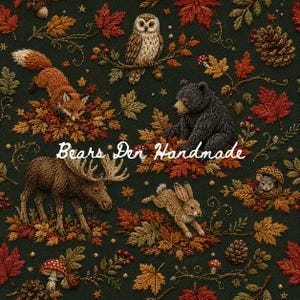 May include: A dark green fabric featuring an intricate embroidered pattern of a fox, owl, black bear, moose, and rabbit amidst autumn leaves, pinecones, mushrooms, and acorns. The text Bears Den Handmade is centered in white cursive script.