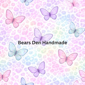 May include: A repeating pattern of pastel butterflies in pink, purple, and blue on a rainbow leopard print background. The text "Bears Den Handmade" is displayed in black.