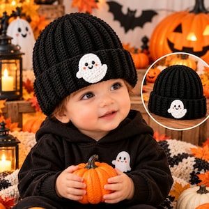 May include: A black ribbed knit beanie featuring a white crocheted ghost patch on the front cuff. The hat is made of yarn and has a folded brim design. The ghost patch has embroidered black eyes and a small smile, providing a simple, clear detail.