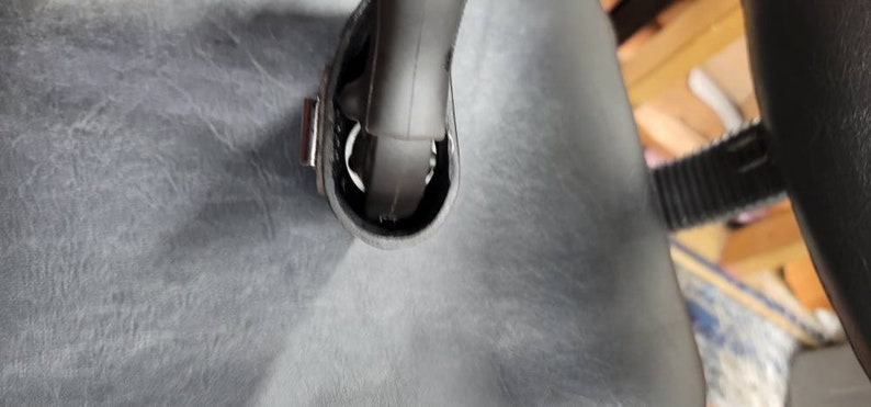 May include: Close-up of a black leather bag with a silver buckle and a black strap. The strap is attached to the bag with a metal loop.