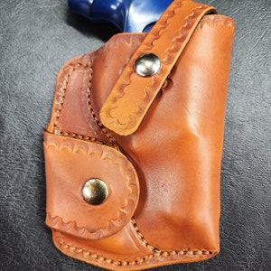 Belt clip holster for Smith and Wesson J frame snubby 38 with ammo pocket and retention strap.
