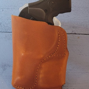 May include: A brown leather holster for a small handgun. The holster has a stitched design and is made of a high-quality material.