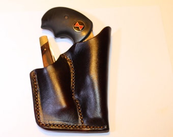 Könnte beinhalten: Ein braunes Lederholster mit einem genähten Design, das eine schwarze Pistole und ein Taschenmesser enthält.