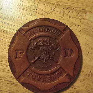 May include: A brown leather patch with a fire department logo. The logo features a crossed axe and a fire hydrant with the text "HARRISON TOWNSHIP" and "FD 23" around it.
