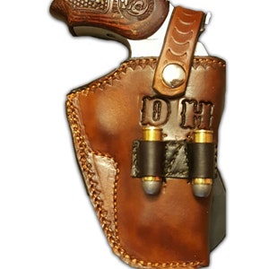 May include: A brown leather holster with a gun inside and two bullet loops on the side. The holster is personalized with the initials "D.H."