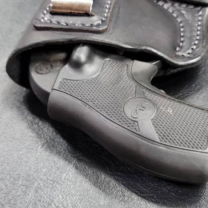 May include: A black leather holster with a silver clip for a small black handgun. The gun has a textured grip and a circular logo that says "CTG".