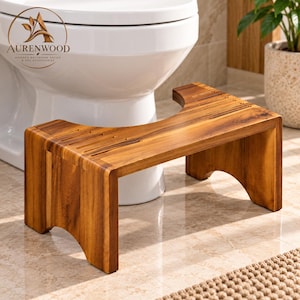May include: A rectangular wooden toilet stool with a natural brown wood grain finish. The stool features a curved cutout along the center edge, four sturdy legs with arched cutouts at the base, and grooved lines on the top surface.