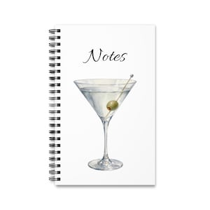 Può includere: Un taccuino a spirale bianco con un'illustrazione ad acquerello di un bicchiere da martini riempito con un liquido trasparente e un'oliva verde su uno stuzzicadenti. La parola Notes è stampata in corsivo nero sopra il bicchiere da martini.