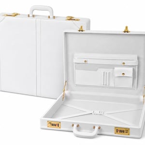 May include: A white hard-shell briefcase with gold-tone hardware, including two combination locks and latches. The interior features a white lining with an organizer panel containing a zippered pocket, slip pockets, pen loops, and elastic straps.
