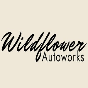Könnte beinhalten: Ein grafisches Logo mit dem schwarzen Text Wildflower Autoworks auf einem einfarbigen cremefarbenen Hintergrund. Das Wort Wildflower ist in einer großen, fließenden Schreibschrift gehalten, während das Wort Autoworks darunter in einer einfachen serifenlosen Schrift erscheint.