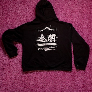 May include: A black hooded sweatshirt featuring a white graphic on the back. The design includes a stylized mountain peak, Japanese kanji characters, the text "All out speed," and additional Japanese text printed in a circular white distressed frame.