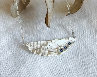 Three blue sapphires nestled in textured recycled sterling silver half moon