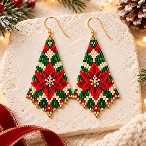 May include: A pair of triangular beaded earrings featuring a poinsettia flower pattern in red, dark green, and cream colors. The earrings are crafted with small glass beads and finished with gold-toned metal ear wires for pierced ears.