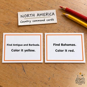 Op de afbeelding: Twee witte rechthoekige opdrachtkaarten met oranje randen, elk voorzien van instructies in zwarte tekst. Eén kaart leest, Find Antigua and Barbuda. Color it yellow. De andere leest, Find Bahamas. Color it red. Een label erboven leest, NORTH AMERICA Country command cards.