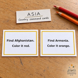 May include: A set of white rectangular cards with yellow borders and black text. One card reads ASIA Country command cards. Another card reads Find Afghanistan. Color it red. The third card reads Find Armenia. Color it orange. Two pencils are present.