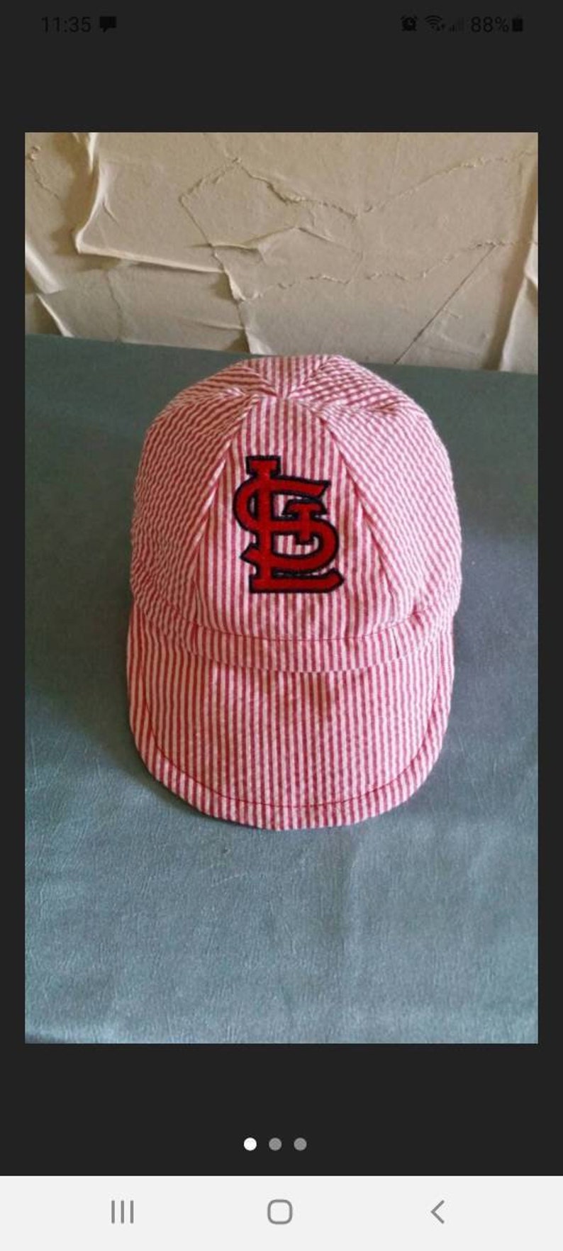 May include: A pink and white striped baseball cap with a red and black embroidered "S" on the front.