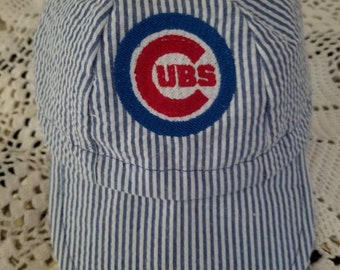 May include: A blue and white striped baseball cap with a red and blue Chicago Cubs logo.
