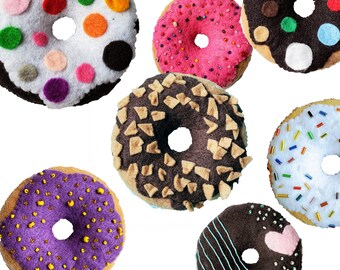 May include: Seven felt donuts in various colors and designs. The donuts are decorated with sprinkles, chocolate chips, and other toppings.