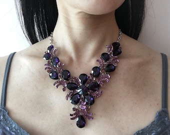 May include: A silver and purple statement necklace with a large flower design and dangling teardrop crystals.