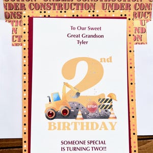 May include: A birthday card with a construction theme. The card features a yellow excavator, the number 2, and the words "BIRTHDAY" and "SOMEONE SPECIAL IS TURNING TWO!!" The card is addressed to "To Our Sweet Great Grandson Tyler."