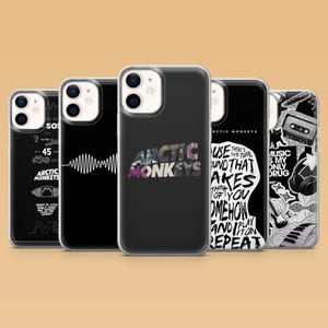 May include: Five clear phone cases featuring Arctic Monkeys designs. The cases display various black and white graphics, including sound waves, song lyrics, a cassette tape, headphones, and the band name in bold, stylized lettering on a black background.