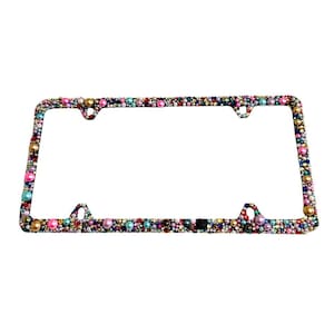 May include: A rectangular license plate frame completely covered in a dense arrangement of small, multicolored beads and pearls. The surface features a vibrant mix of pink, blue, gold, and white spherical accents, creating a textured, multi-dimensional appearance across the entire border of the frame.