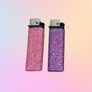 May include: Two glitter lighters, one pink and one purple.
