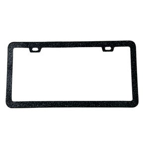 May include: A black license plate frame with a glittery texture. The rectangular frame has rounded corners and two mounting holes at the top. The frame is designed to hold a standard U.S. license plate.