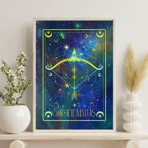 Puede incluir: Impresión artística enmarcada del signo zodiacal Sagitario. La obra presenta un diseño celestial con un símbolo de flecha y arco, estrellas y la palabra "SAGITTARIUS". La paleta de colores incluye tonos de azul, verde y amarillo, creando una estética cósmica. La impresión está enmarcada.