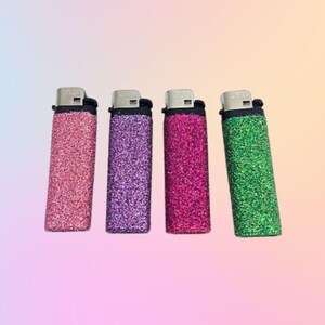 May include: Four lighters with glitter covers. The lighters are pink, purple, red, and green.