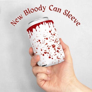 Op de afbeelding: Een witte blikkoelhouder met rood bloedspatten en een ontwerp van druppelen bloed. De tekst "New Bloody Can Sleeve" staat rond de bovenkant van de koelhouder.