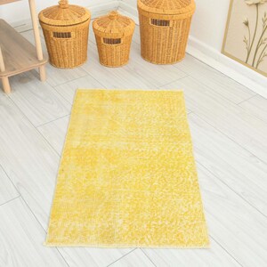 May include: A rectangular area rug featuring a vibrant yellow color with a distressed, faded texture. The rug has a low-pile construction and a consistent, solid yellow hue throughout its surface, creating a bright and uniform appearance.
