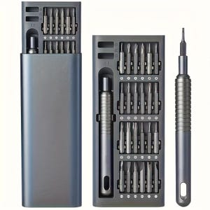 May include: A dark gray precision screwdriver set featuring a rectangular storage case with a sliding tray. The set includes a cylindrical handle and numerous interchangeable metal bits organized in rows within the internal tray compartments.