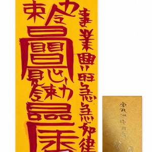 May include: A rectangular yellow paper talisman featuring bold red calligraphic characters and a small white label with the text Business Prosperity. Beside it is a smaller, metallic gold rectangular card with embossed gold script.