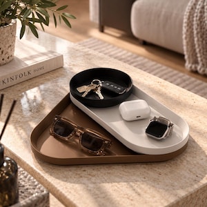 May include: A set of three nested trays in black, white, and brown with rounded edges. The black tray holds keys, the white tray contains white wireless earbuds and a smartwatch, and the brown tray holds a pair of brown-tinted sunglasses.